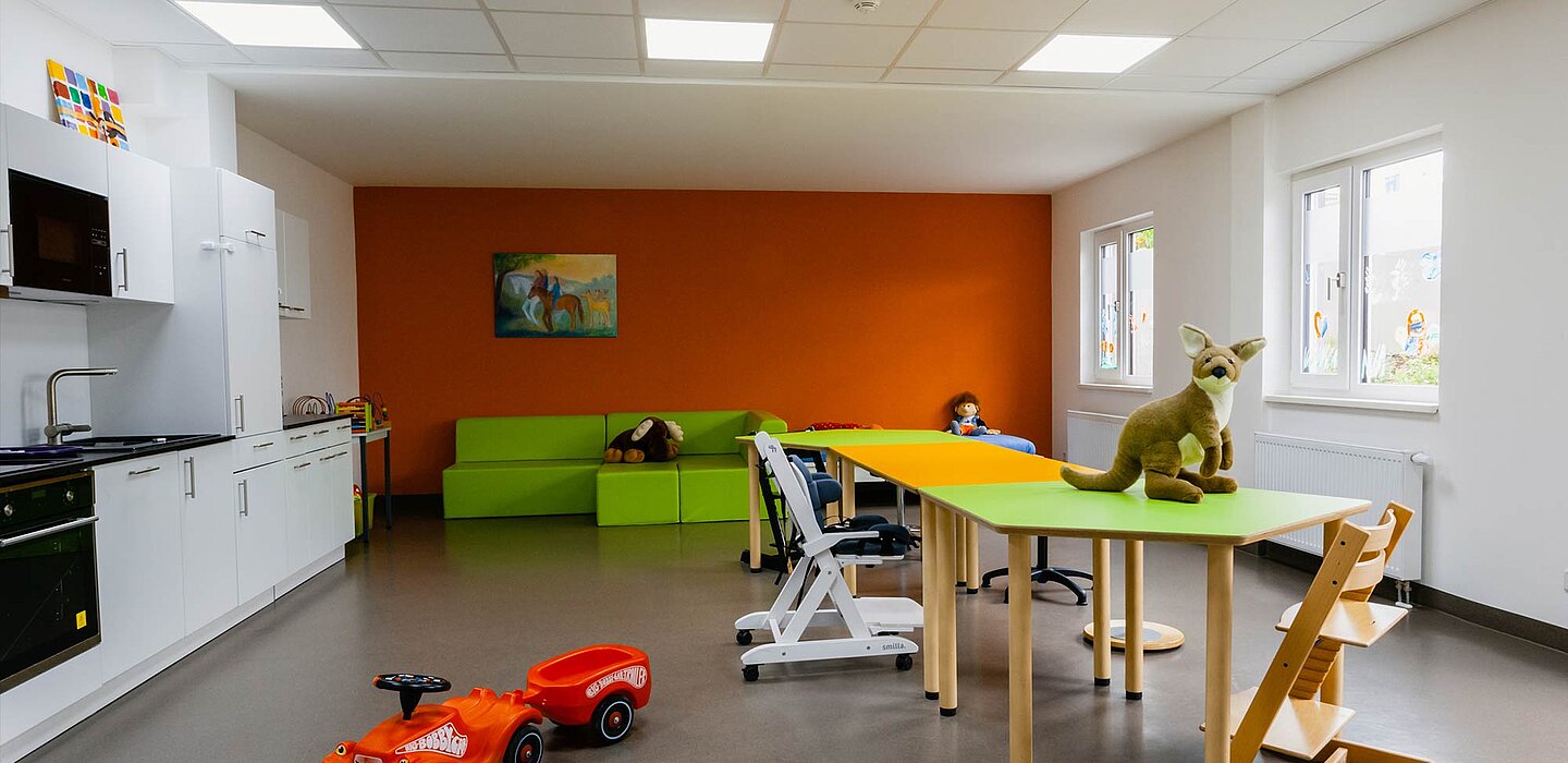 Innenaufnahme eines Raumes im Kinderhaus Nesthäkchen. Links eine Küchenzeile, in der Mitte ein Tisch mit Spielzeug und dem Känguru darauf. 